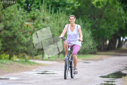 Image of Girl riding a bicycle on a rainy warm summer morning