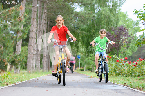 Image of Two girls ride a bike on a bike path