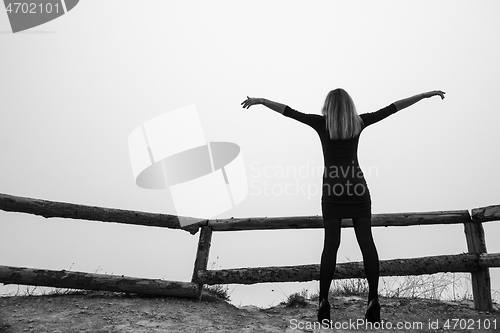 Image of The girl spread her arms up while standing on the observation deck in an early foggy morning