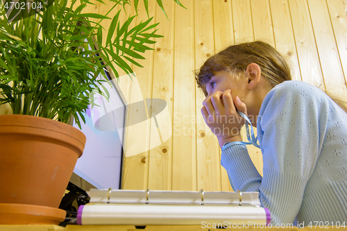 Image of A student sits in front of the computer during distance learning and looks thoughtfully at the screen