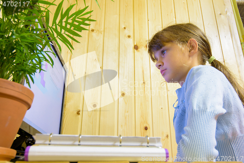 Image of The student sits at the table in front of the monitor and carefully reads the task