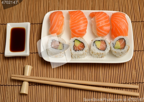 Image of chopsticks, soy sauce and sushi on the mat