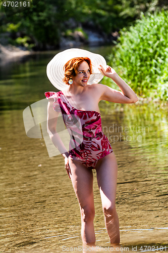 Image of Red-haired woman standing in water on the beach