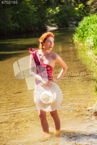 Image of Woman in bathing suit and hat in hand