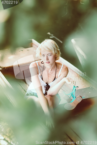 Image of Woman relaxing on the vintage wooden boat.