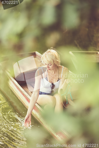 Image of Woman relaxing on the vintage wooden boat.