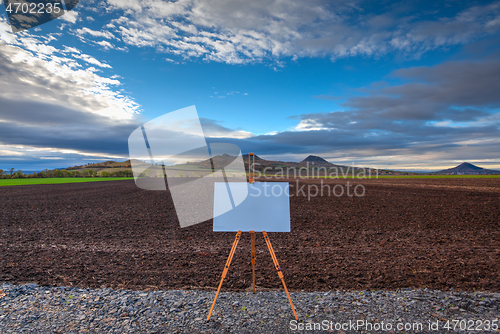 Image of Blank art board and realistic wooden easel on the road. 
