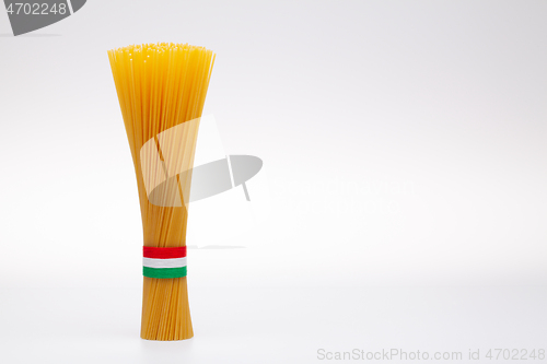 Image of Bundle of spaghetti and Italian flag on the white table