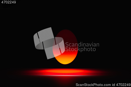 Image of Red egg levitating over a black glass table 