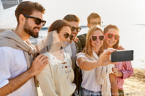 Image of happy friends taking selfie on summer beach