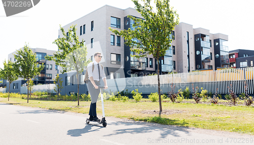 Image of businessman with backpack riding electric scooter