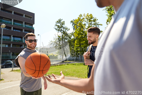 Image of group of male friends playing street basketball