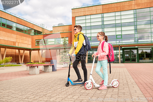 Image of happy school children with backpacks and scooters