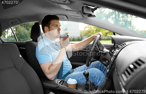 Image of man driving car and recording voice by smartphone