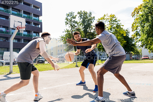 Image of group of male friends playing street basketball