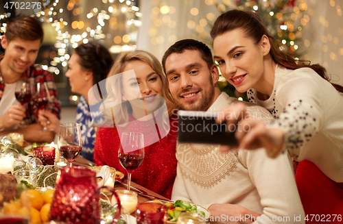 Image of friends having christmas dinner and taking selfie