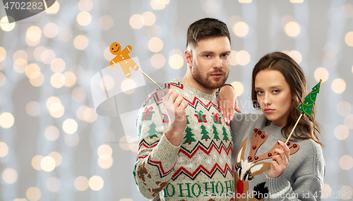 Image of couple with christmas party props in ugly sweaters