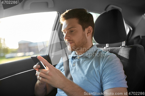 Image of male passenger using smartphone in taxi car