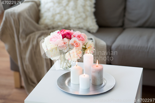 Image of candles burning on table and flowers at cozy home