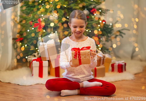 Image of smiling girl with christmas gift at home