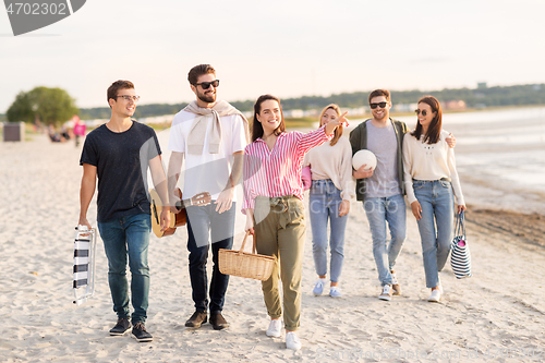 Image of happy friends walking along summer beach