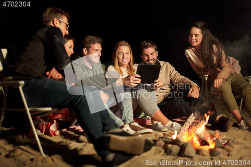 Image of friends with tablet pc at night camp fire on beach