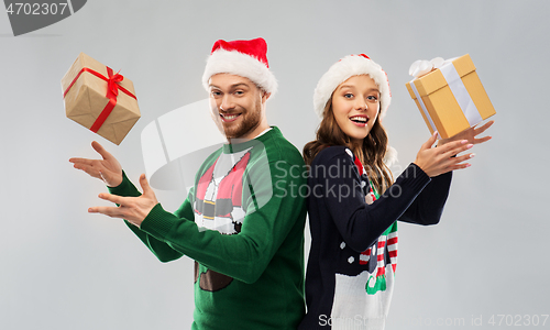 Image of happy couple in christmas sweaters with gifts