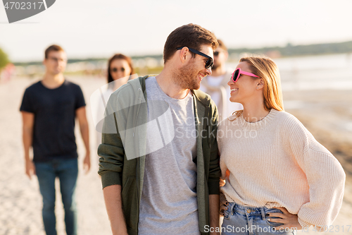 Image of happy friends walking along summer beach