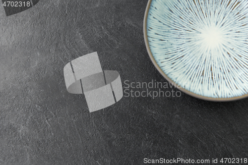 Image of close up of blue ceramic plate on slate background