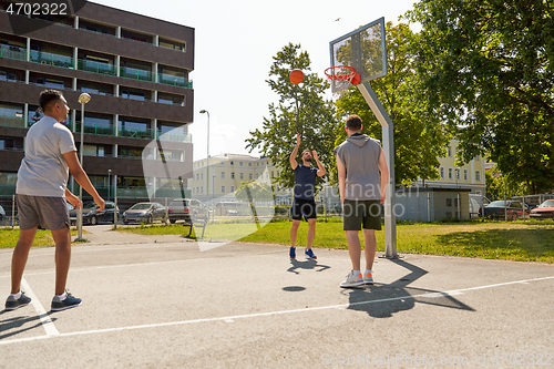 Image of group of male friends playing street basketball