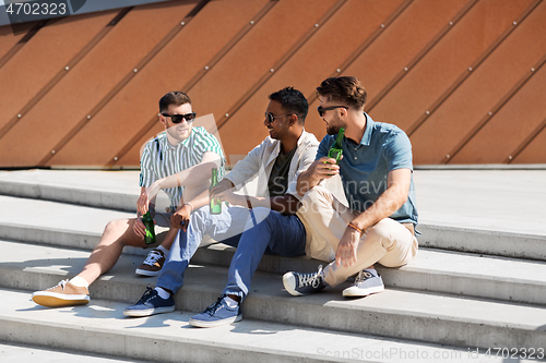 Image of happy male friends drinking beer on street