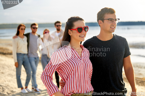 Image of happy friends walking along summer beach