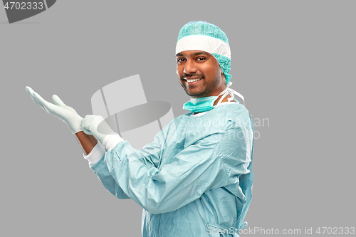 Image of indian male doctor or surgeon putting glove on