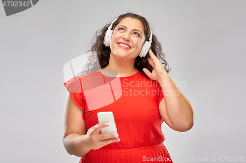 Image of woman in headphones listens to music on smartphone