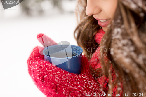 Image of happy young woman with tea cup in winter park