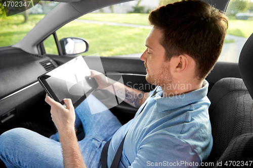 Image of male passenger using tablet computer in taxi car