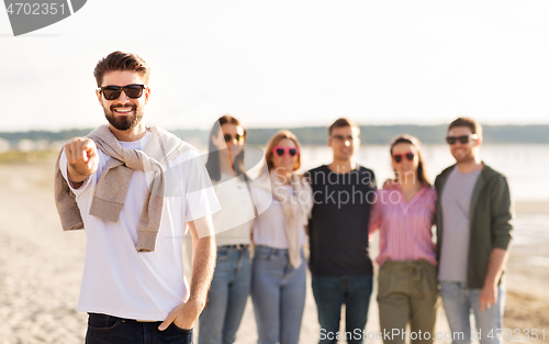 Image of happy man with friends on beach in summer