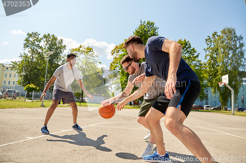 Image of group of male friends playing street basketball