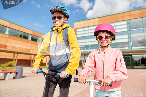 Image of happy school children with backpacks and scooters