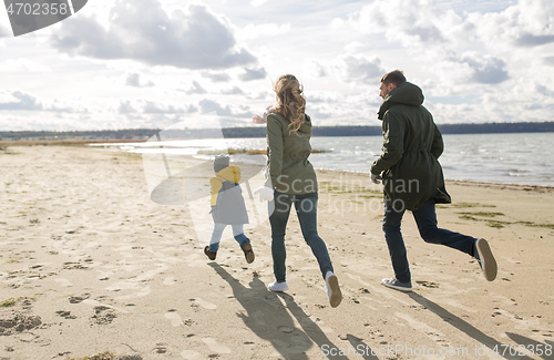 Image of happy family running along autumn beach