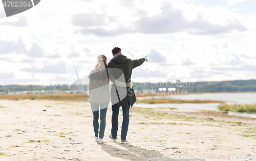 Image of couple walking along autumn beach and hugging