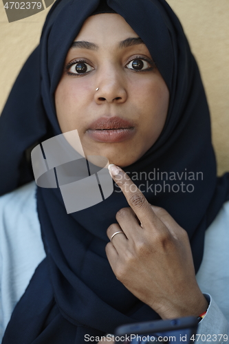 Image of african woman using smartphone wearing traditional islamic clothes