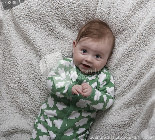 Image of cute little baby playing with hands and smiling