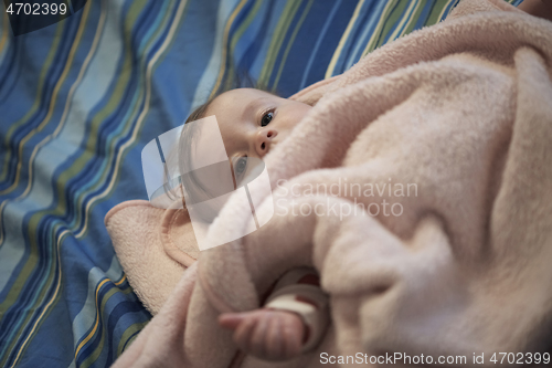 Image of cute little baby playing with hands and smiling