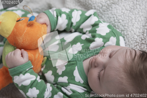 Image of cute little baby playing with hands and smiling