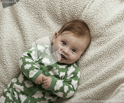 Image of cute little baby playing with hands and smiling