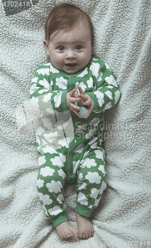 Image of cute little baby playing with hands and smiling