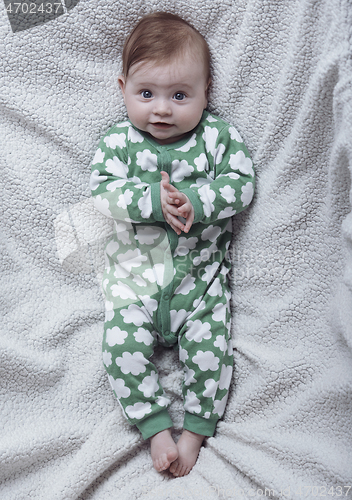 Image of cute little baby playing with hands and smiling