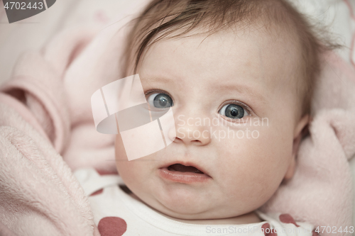 Image of cute little baby playing with hands and smiling