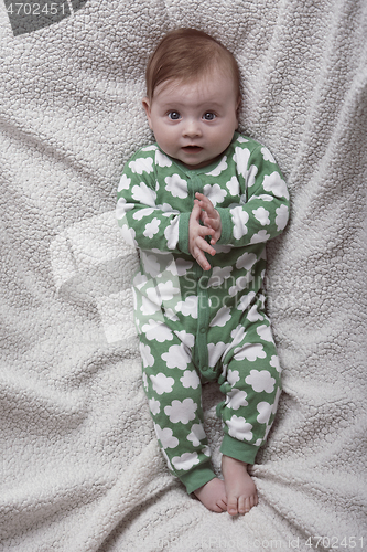 Image of cute little baby playing with hands and smiling